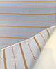 Close view of Sunbrella Linger Slate fabric weave with tan and brown checkerboard stripes on light blue